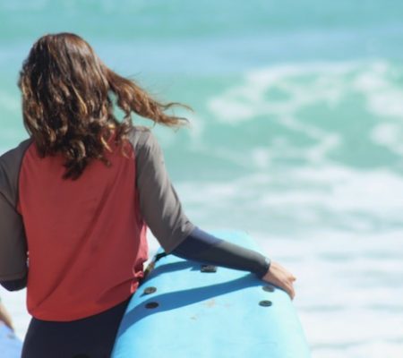 surf school student with surfboard on a beach in fuerteventura